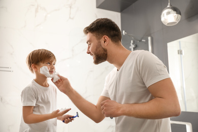 Photo of Dad applying shaving foam onto son's face in bathroom