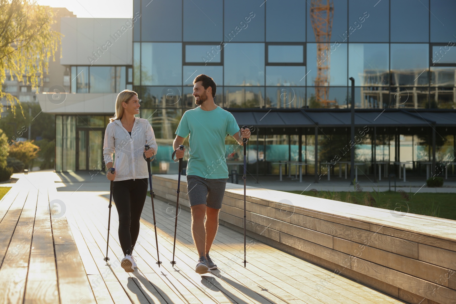 Photo of Happy couple practicing Nordic walking with poles outdoors