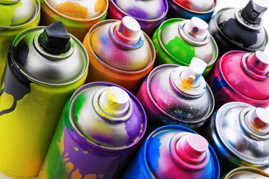Photo of Used cans of spray paints as background, closeup. Graffiti supplies