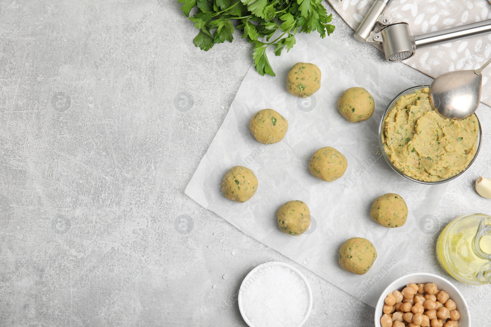 Photo of Raw falafel balls and ingredients on grey table, flat lay. Space for text