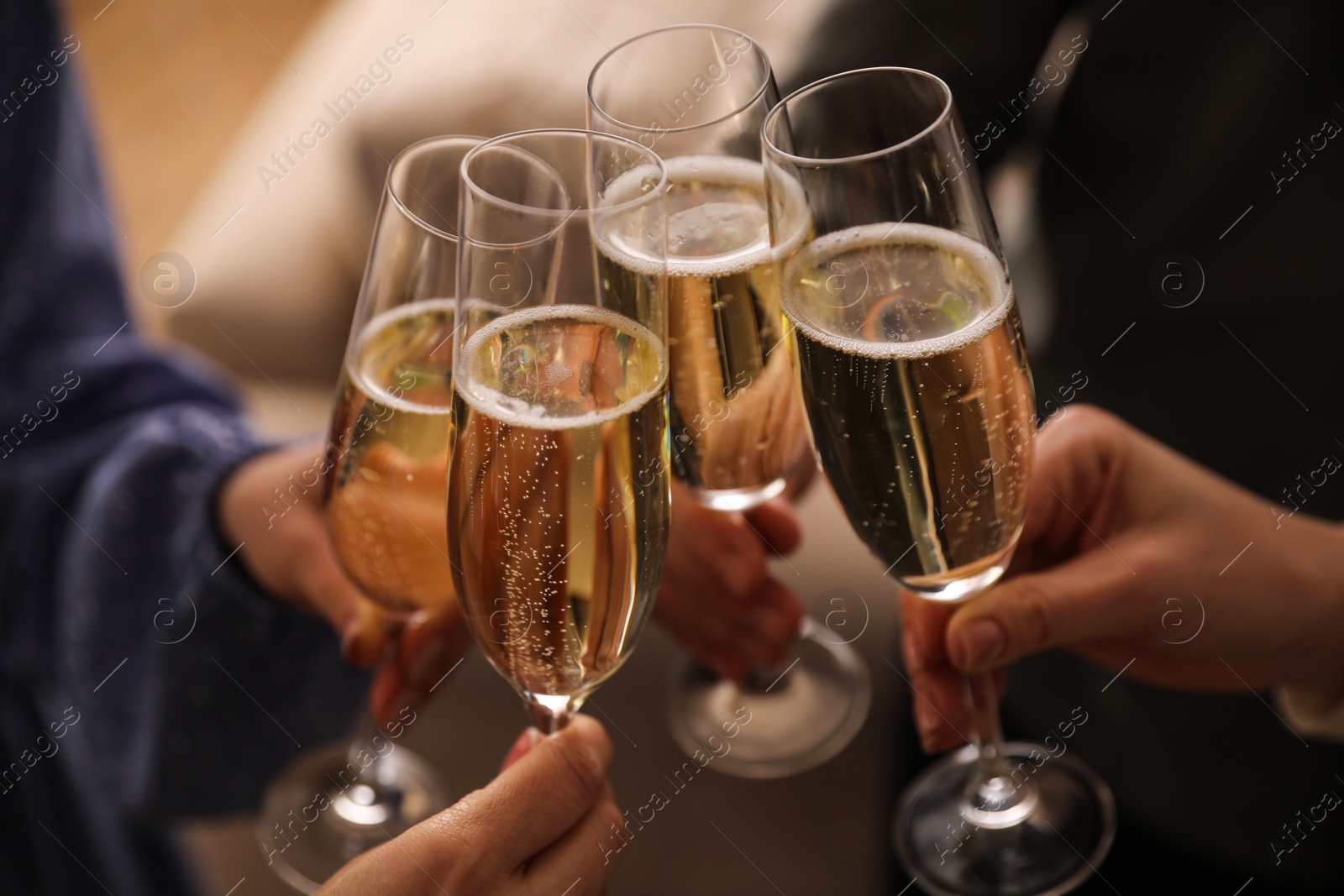 Photo of People clinking glasses with champagne at home, closeup