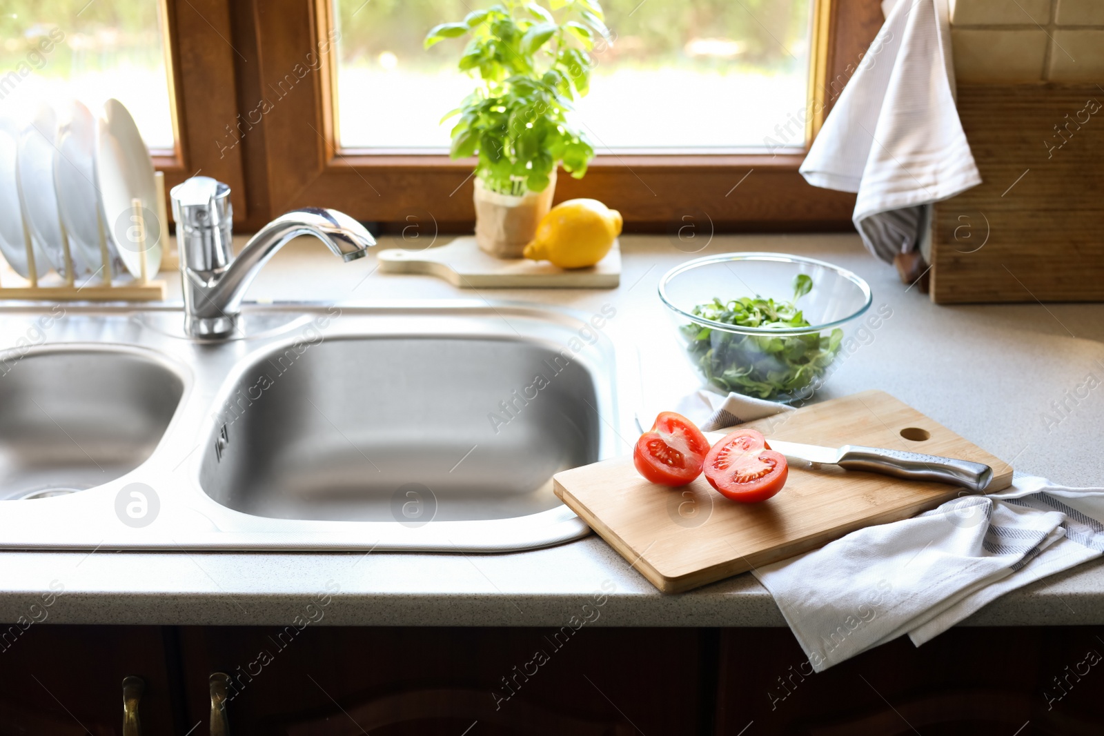 Photo of Cut tomato and knife near sink in kitchen