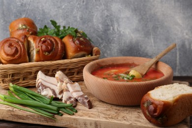 Photo of Delicious pampushky (buns with garlic) and salo served for borsch on wooden board, closeup. Traditional Ukrainian cuisine