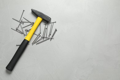 Photo of New hammer and metal nails on grey table, flat lay. Space for text