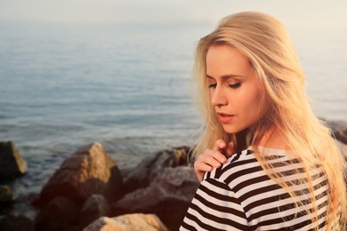 Photo of Beautiful young woman near sea on sunny day, space for text