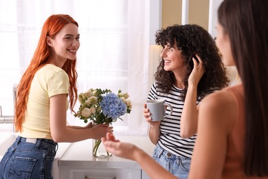 Photo of Happy young friends spending time together in kitchen
