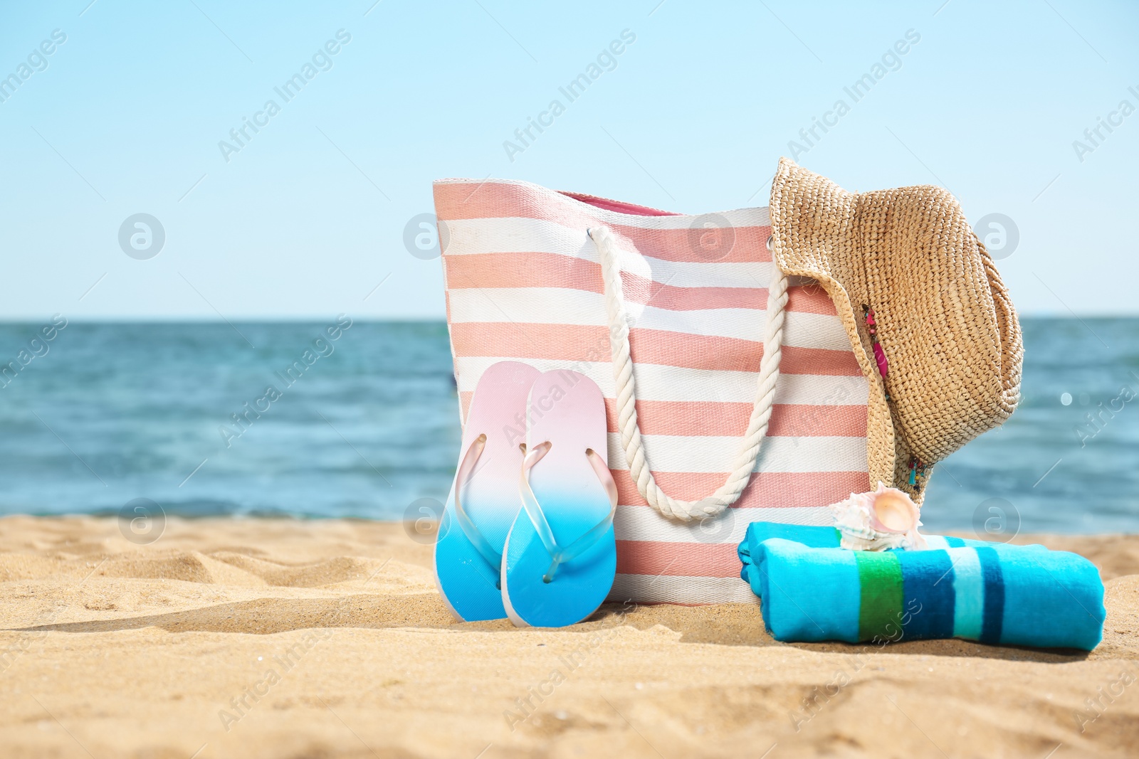 Photo of Stylish beach accessories on sand near sea. Space for text