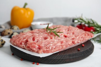 Photo of Raw chicken minced meat with rosemary and spices on white wooden table, closeup