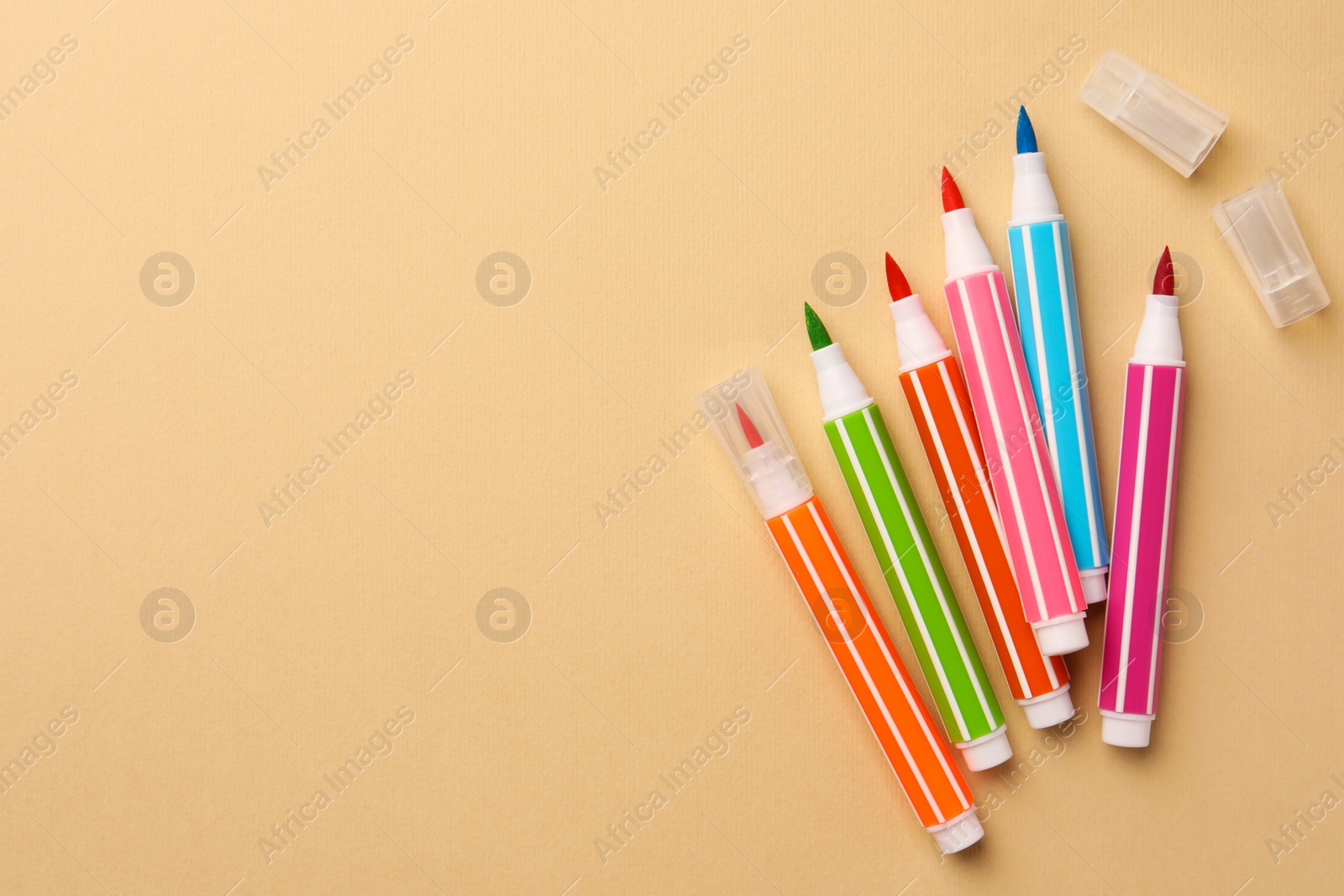 Photo of Many bright markers on beige background, flat lay. Space for text