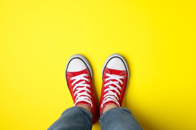 Photo of Woman in stylish gumshoes on yellow background, top view