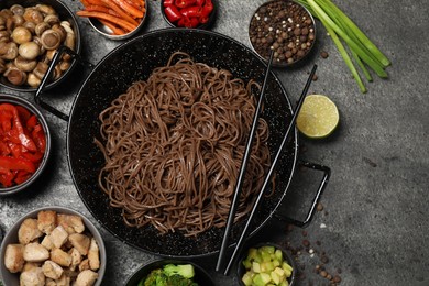 Photo of Wok with noodles, chicken and other products on grey table, flat lay