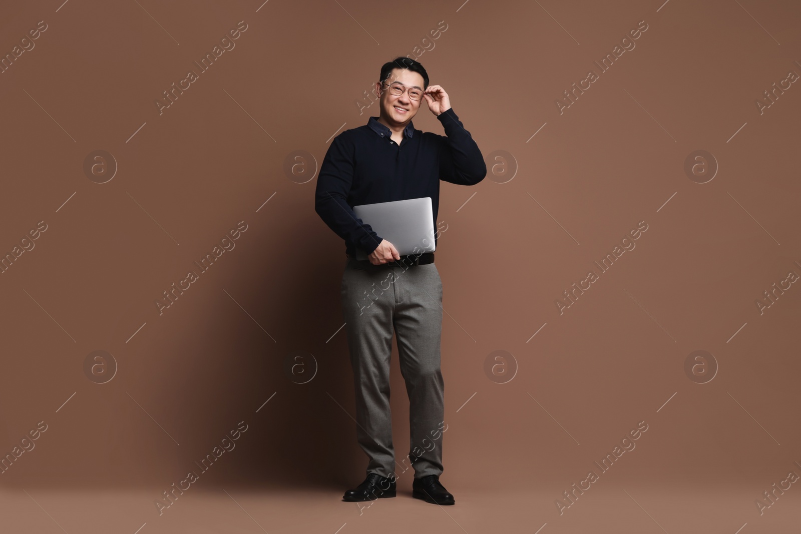 Photo of Full length portrait of happy man with laptop on brown background