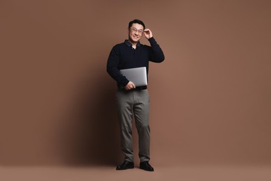 Photo of Full length portrait of happy man with laptop on brown background