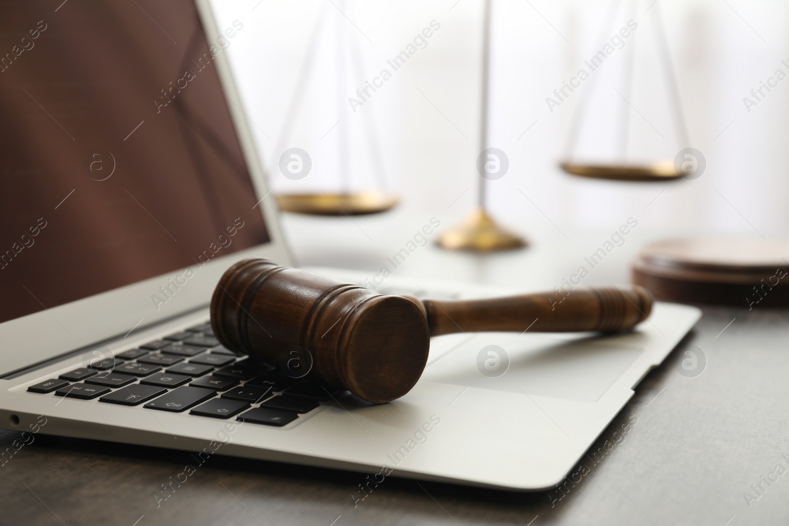 Photo of Laptop, gavel and scales on table, closeup. Cyber crime