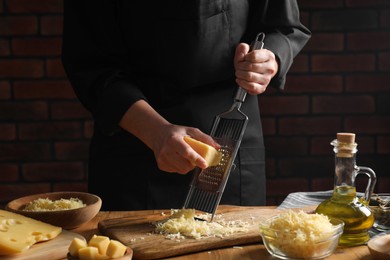 Woman grating cheese at wooden table, closeup