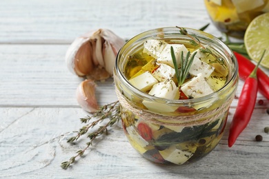 Photo of Composition with pickled feta cheese in jar on white wooden table