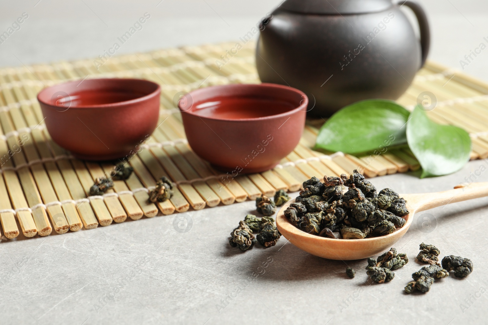 Photo of Composition with spoon of Tie Guan Yin Oolong tea and brewed beverage on grey table