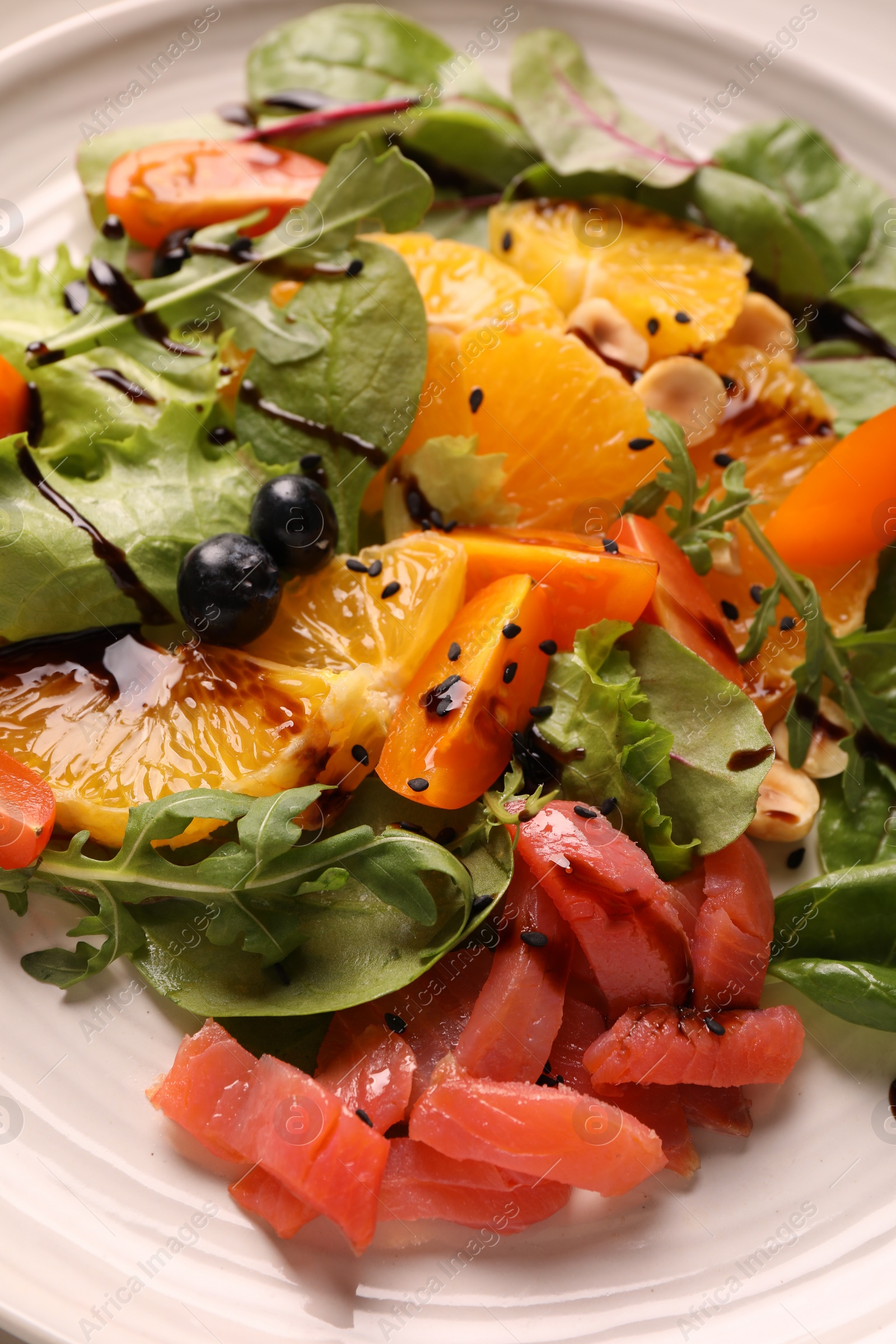 Photo of Delicious salad with salmon on white plate, closeup