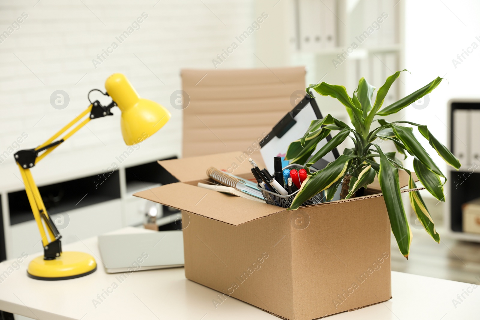 Photo of Cardboard box full of stuff on table in office