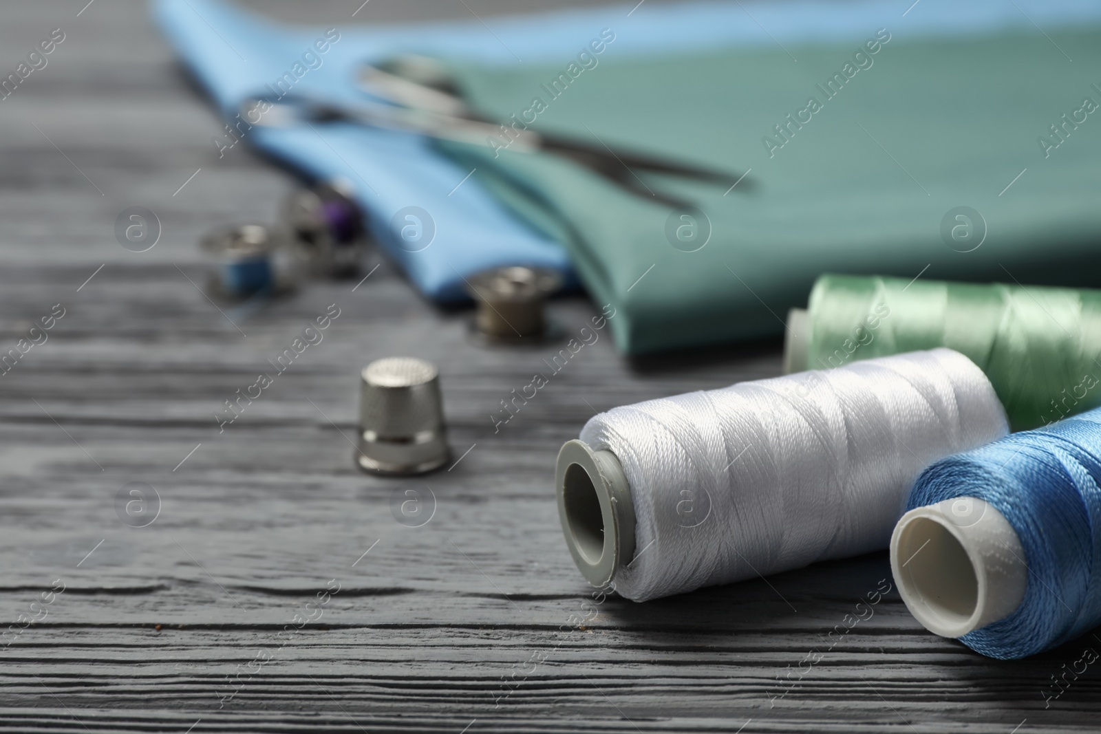 Photo of Sewing threads and accessories on wooden background