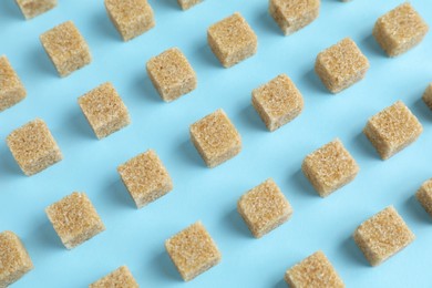 Photo of Brown sugar cubes on light blue background