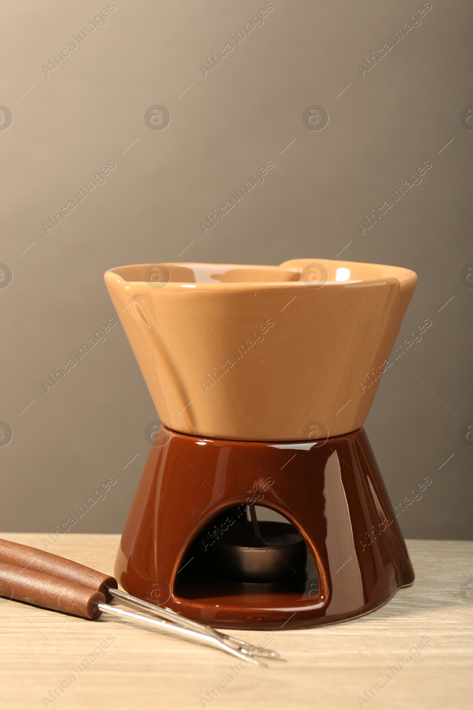 Photo of Fondue set on wooden table. Kitchen equipment