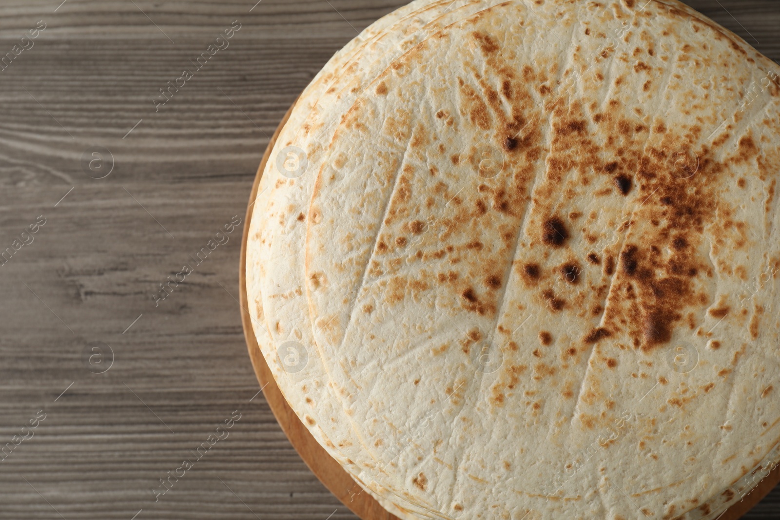 Photo of Many tasty homemade tortillas on wooden table, top view. Space for text