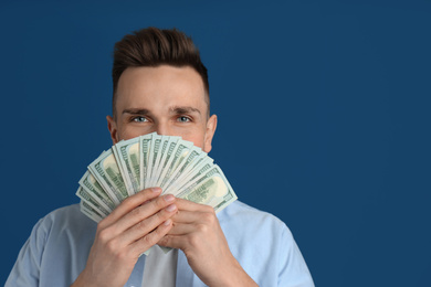 Photo of Happy man with cash money on blue background. Space for text
