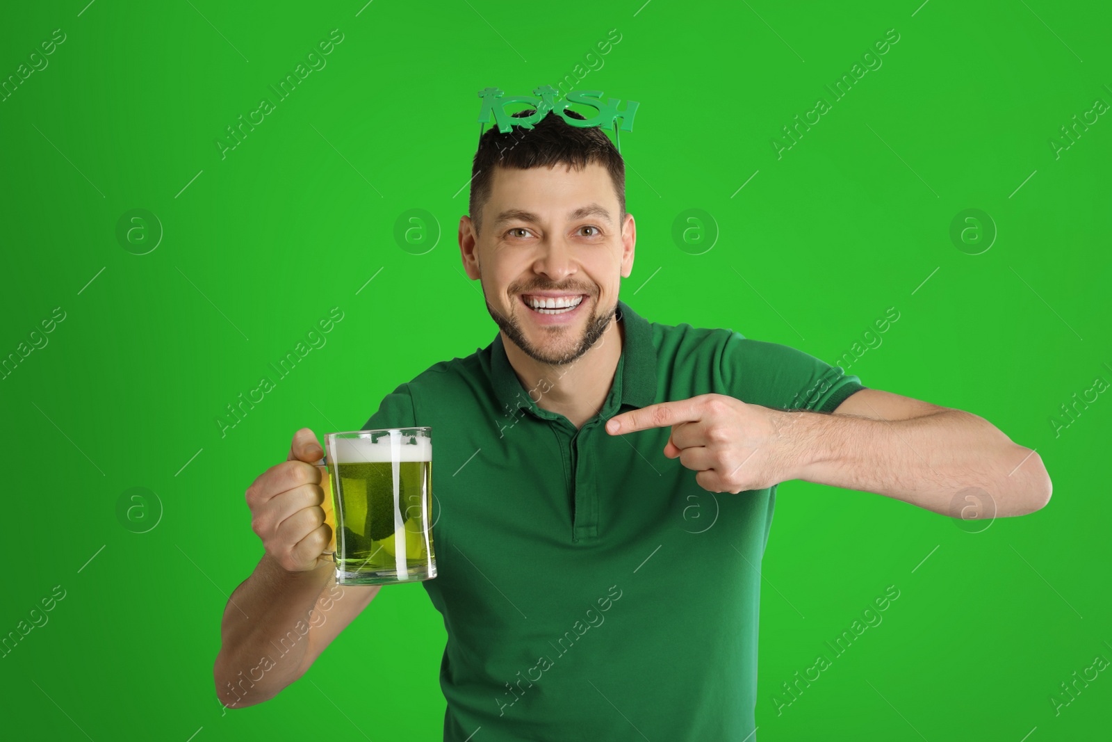 Image of Happy man in St. Patrick's Day outfit with beer on green background