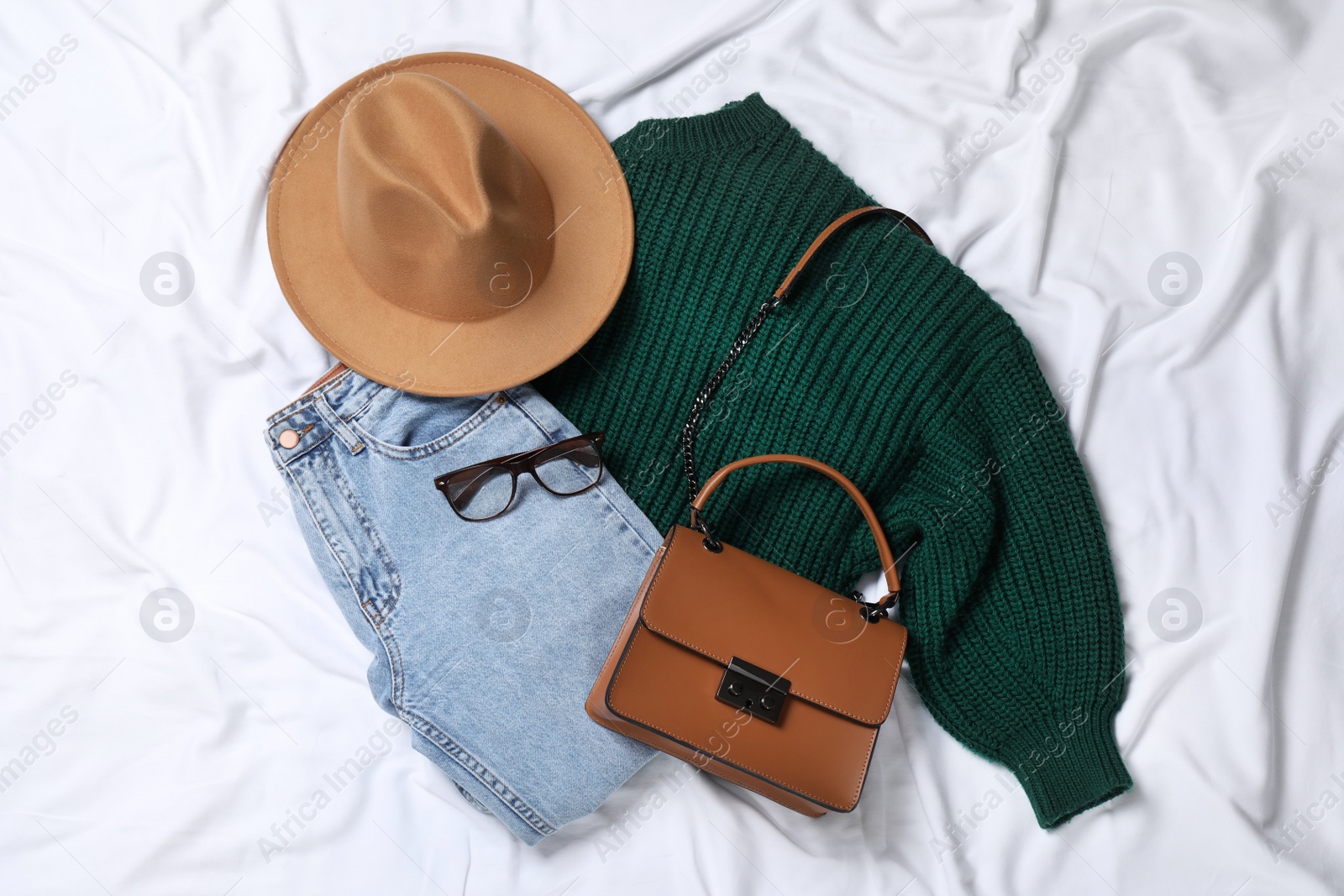 Photo of Flat lay composition with stylish hat and autumn clothes on white fabric