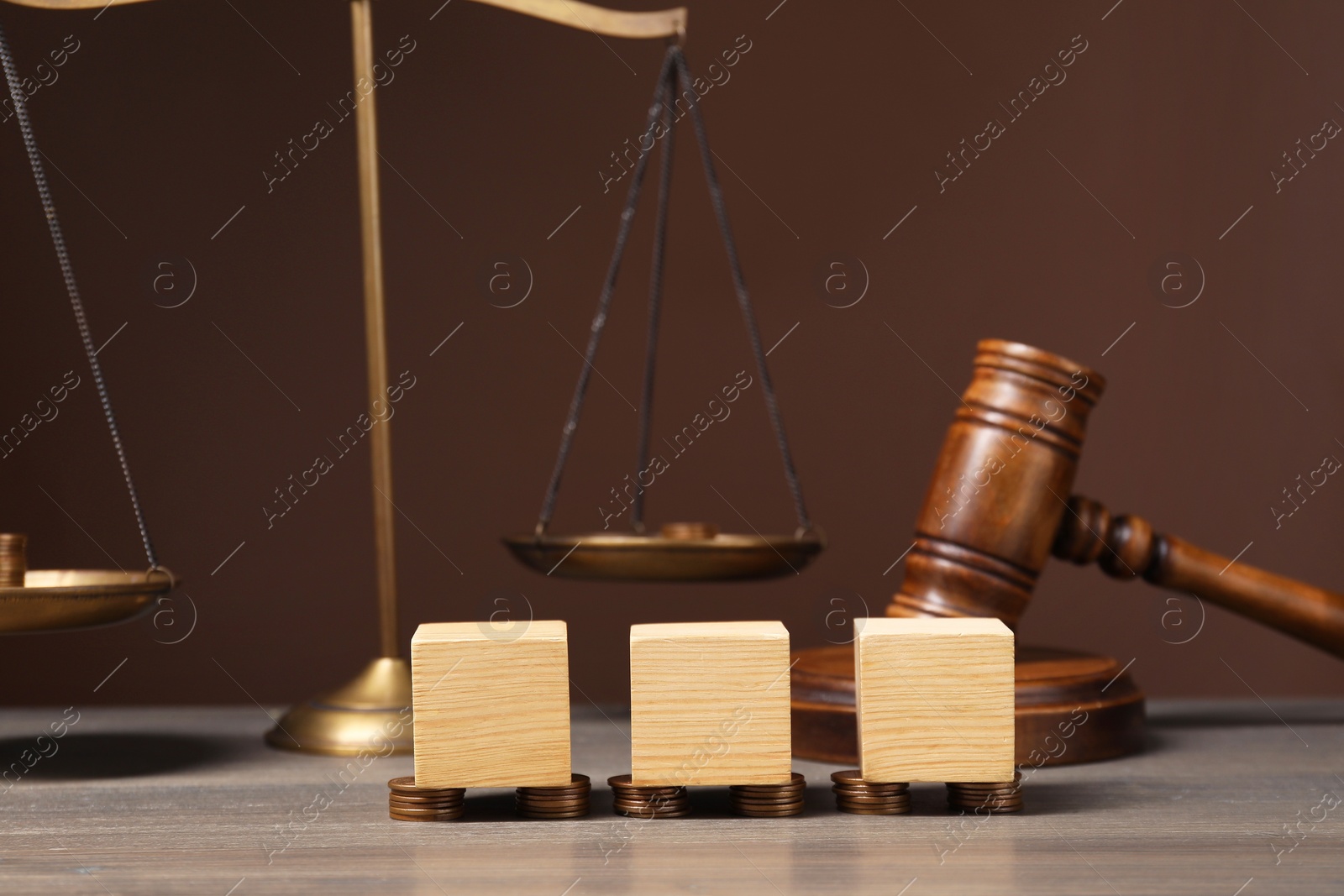 Photo of Law. Blank cubes, coins and gavel on wooden table against brown background