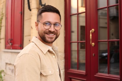 Portrait of handsome bearded man in glasses outdoors, space for text