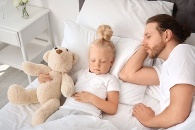 Photo of Father looking at his cute sleeping daughter in bed