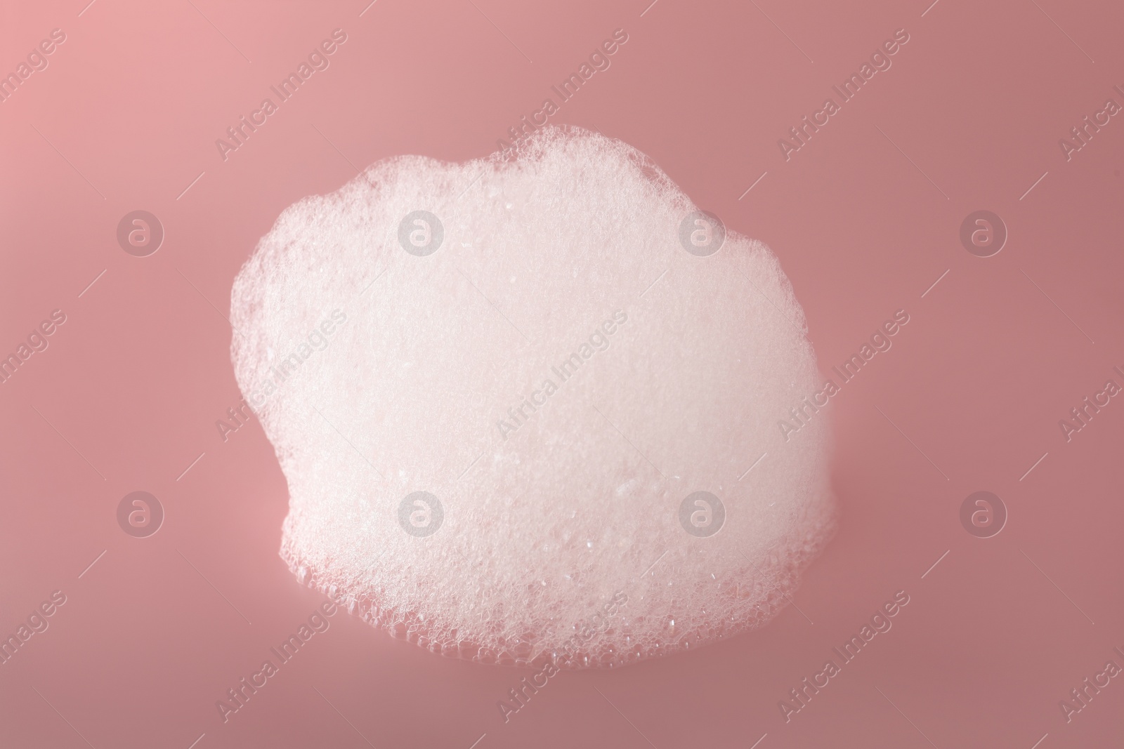 Photo of Drop of fluffy bath foam on pink background