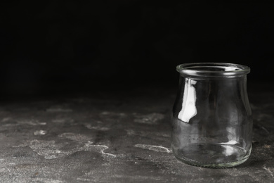 Photo of Empty glass jar on grey stone table, space for text
