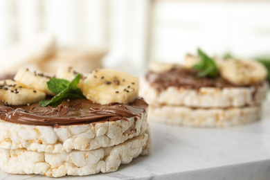 Photo of Puffed rice cakes with chocolate spread, banana and mint on board, closeup. Space for text