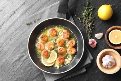 Photo of Delicious scallops with sauce in frying pan and ingredients on dark gray textured table, flat lay