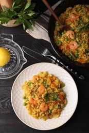 Photo of Tasty rice with shrimps and vegetables served on dark wooden table, flat lay