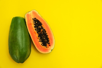 Fresh juicy ripe papayas on yellow background, flat lay. Space for text