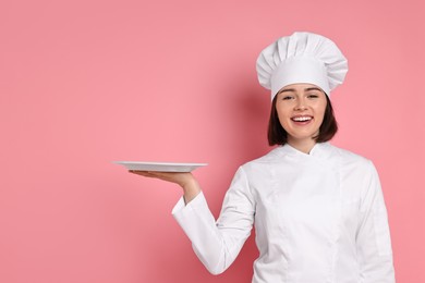 Photo of Happy confectioner with plate on pink background, space for text