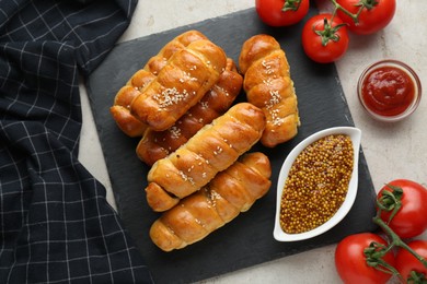 Photo of Delicious sausage rolls and ingredients on beige table, flat lay