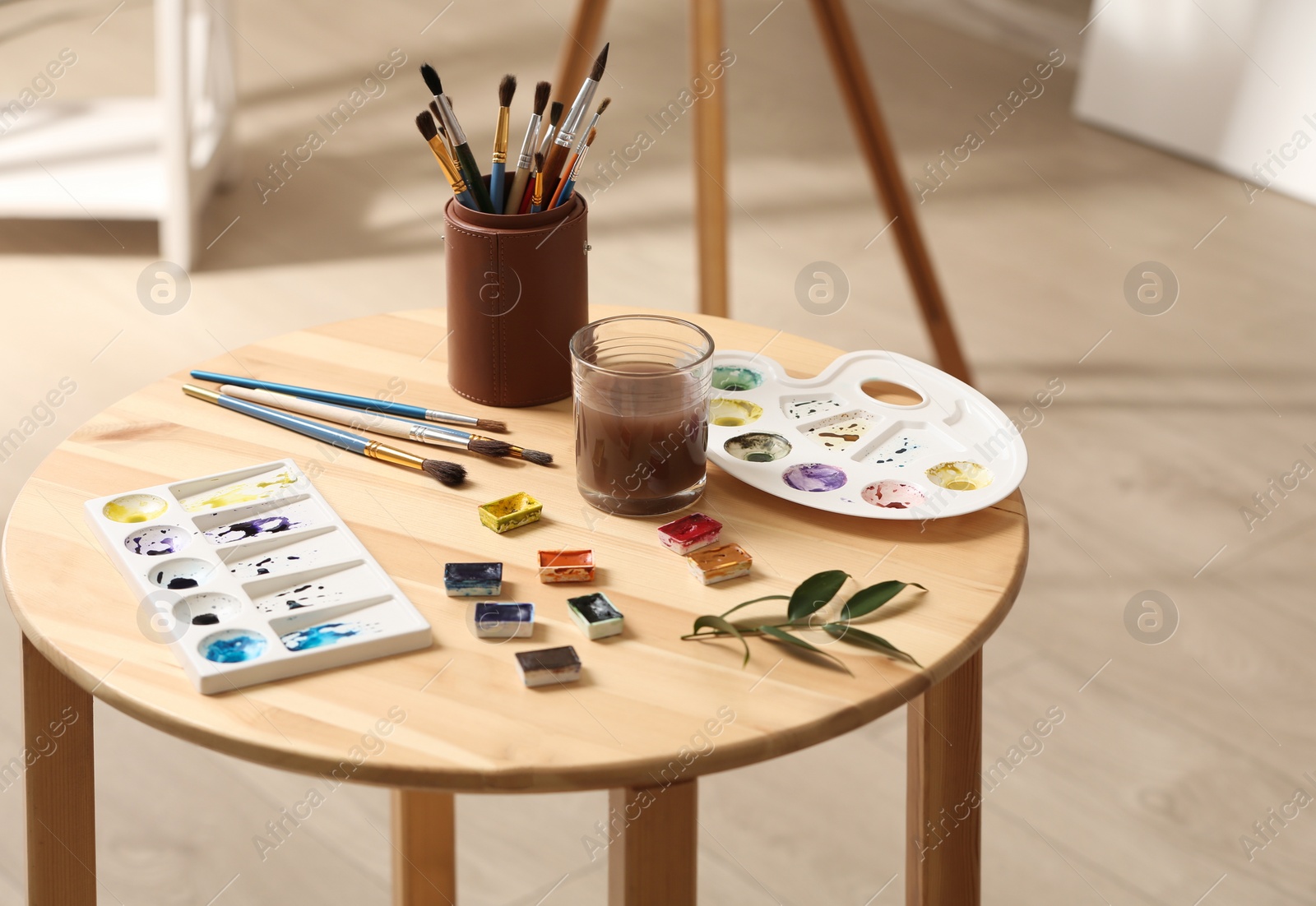 Photo of Composition with watercolor paints on wooden table in workshop