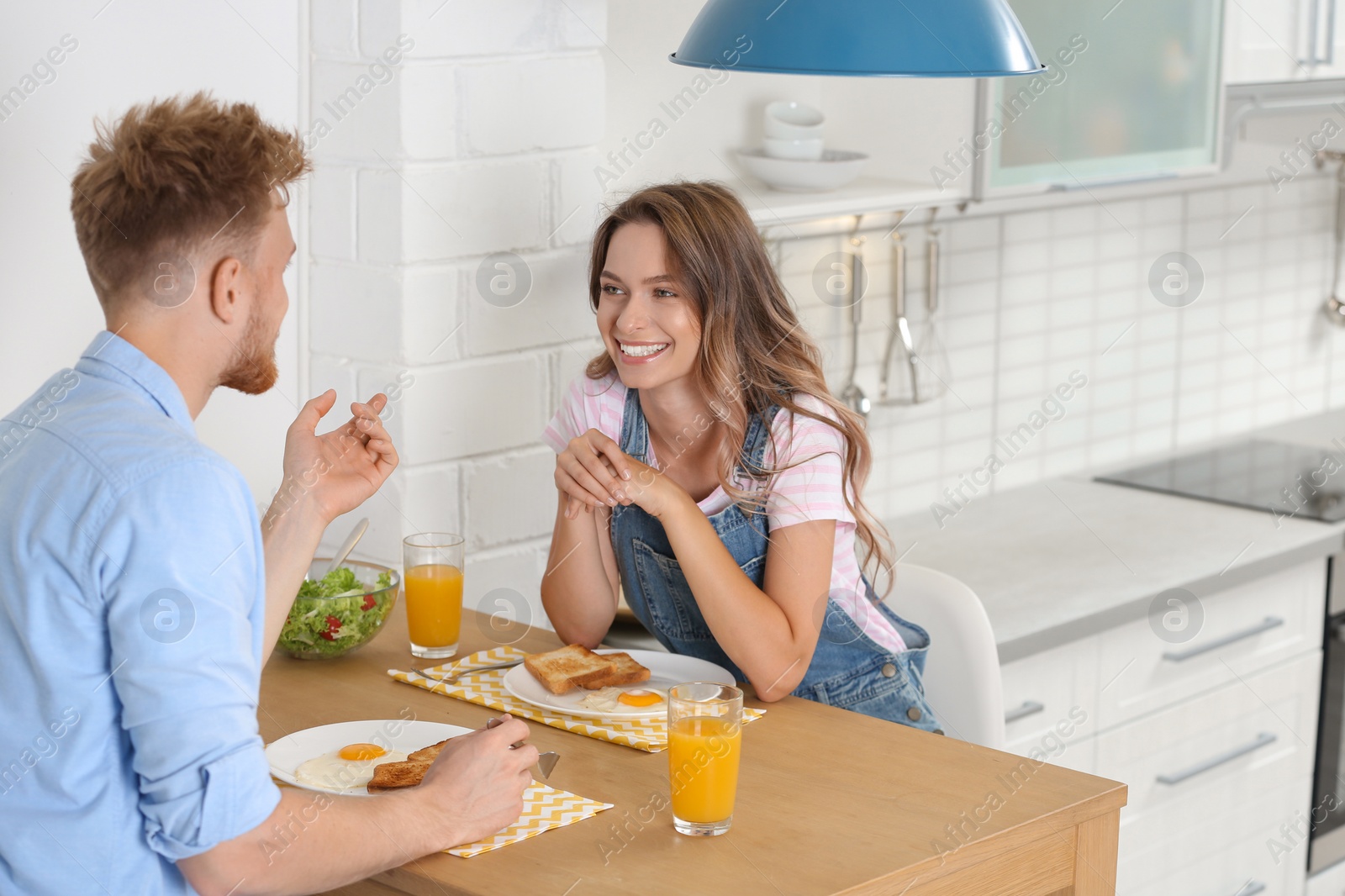 Photo of Happy young couple having breakfast at table in kitchen