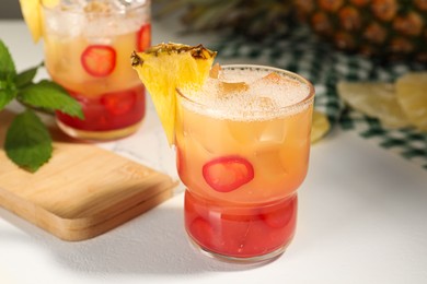 Spicy pineapple cocktail with chili pepper and ice cubes on white table, closeup