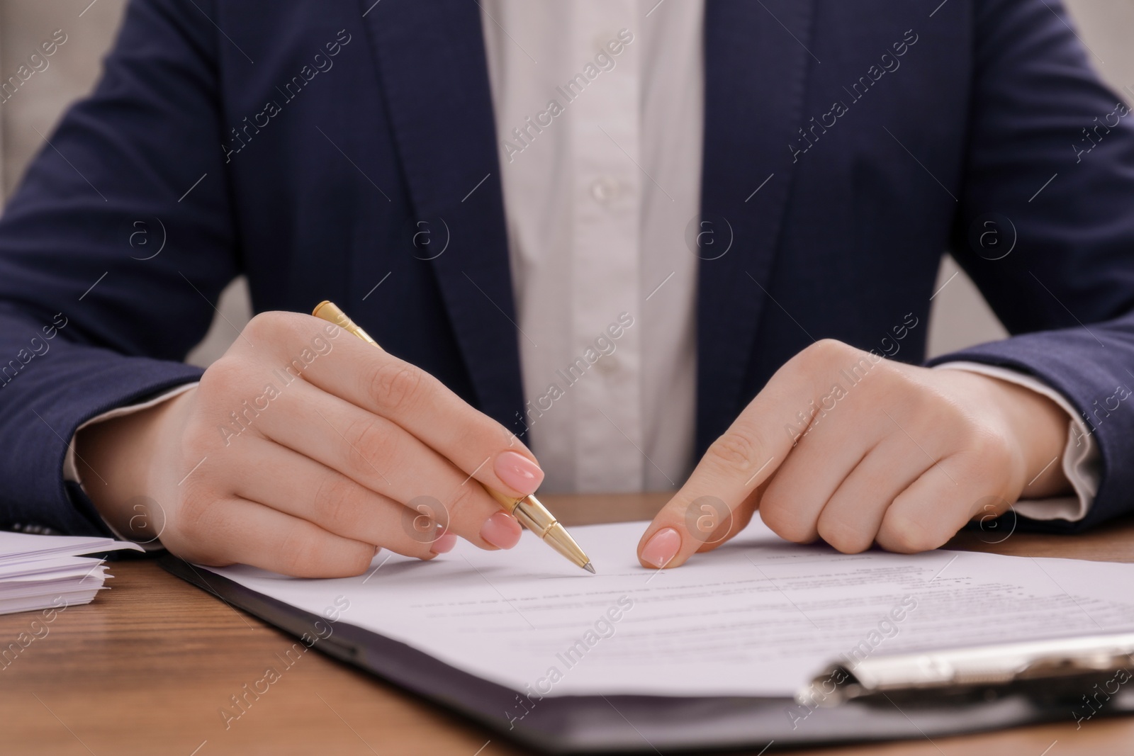 Photo of Woman signing document at wooden table, closeup