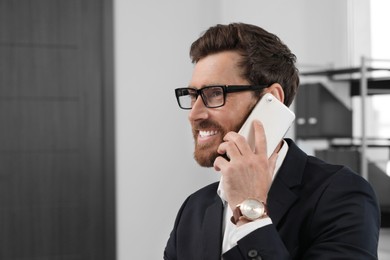 Photo of Happy bearded man talking on smartphone indoors