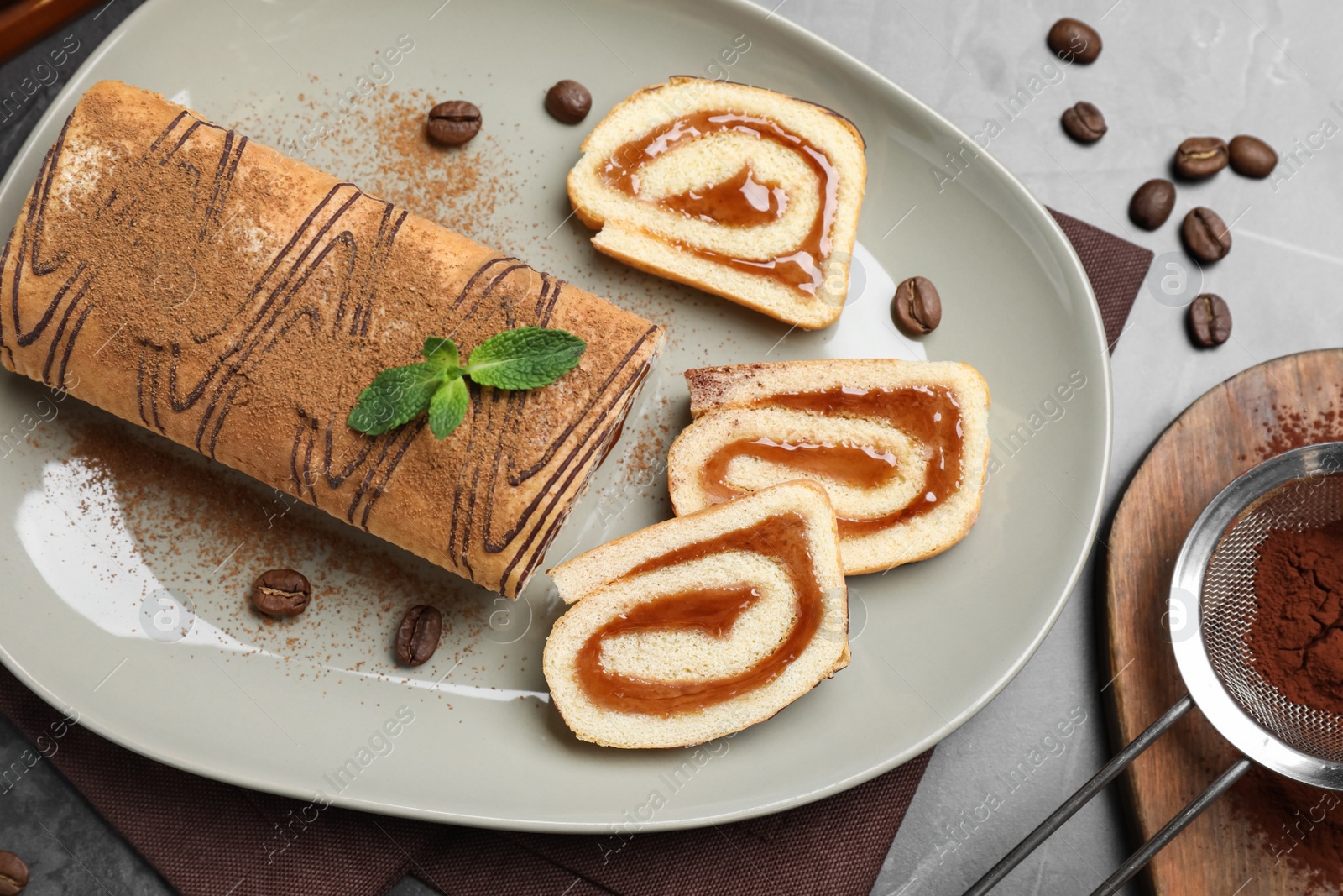 Photo of Tasty cake roll with jam and mint on grey table, flat lay