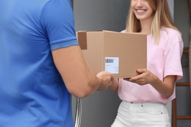Photo of Young woman receiving parcel from courier on doorstep. Delivery service