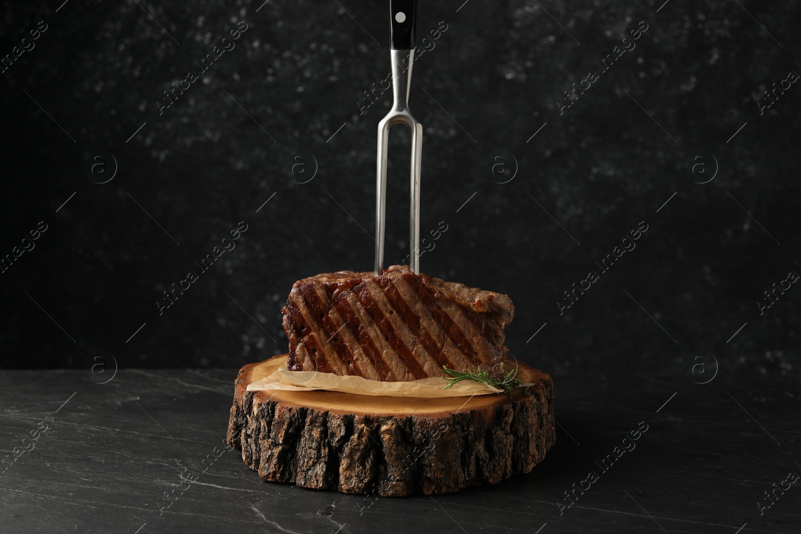 Photo of Delicious grilled beef steak served on dark gray table