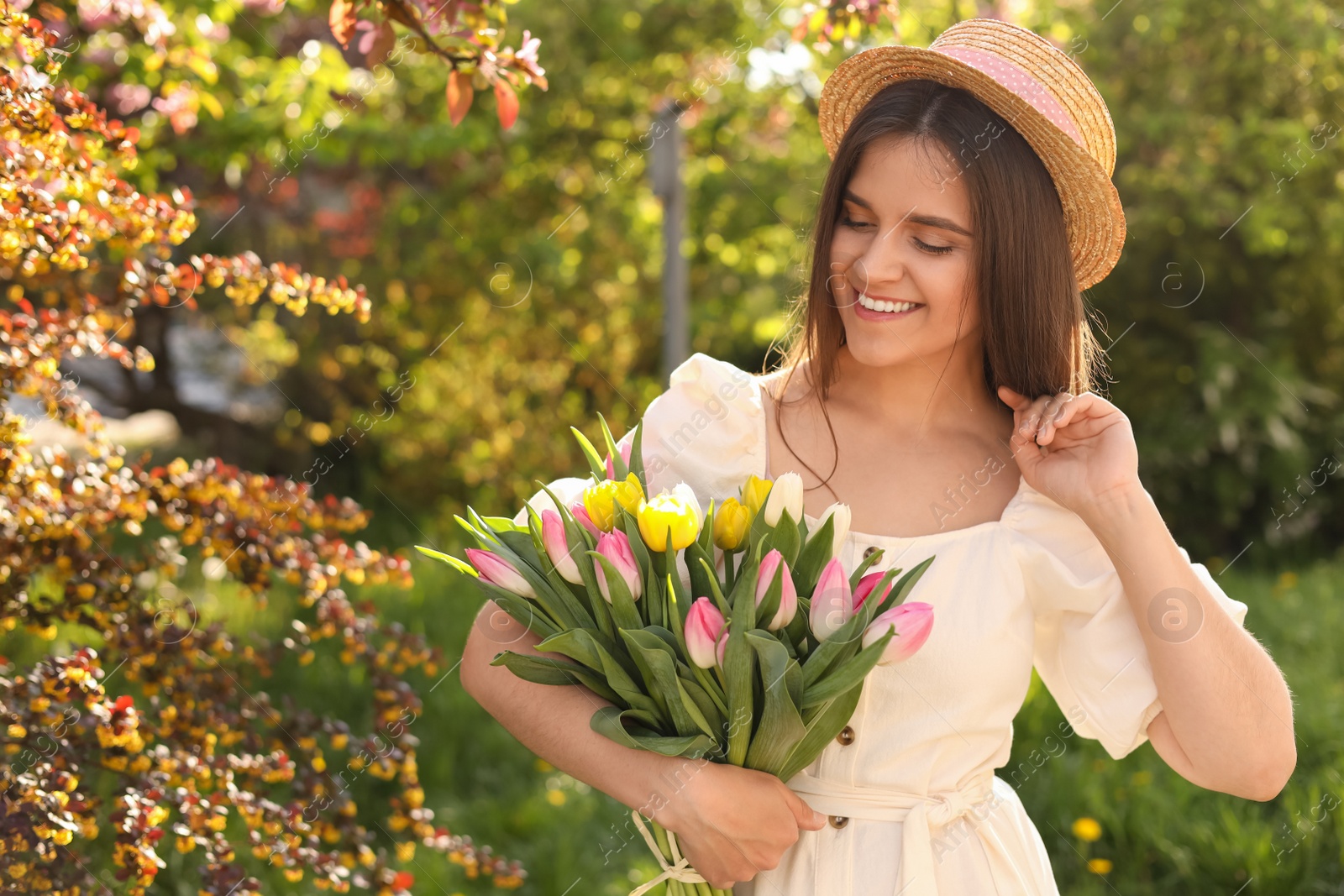 Photo of Beautiful young woman with bouquet of tulips in park on sunny day